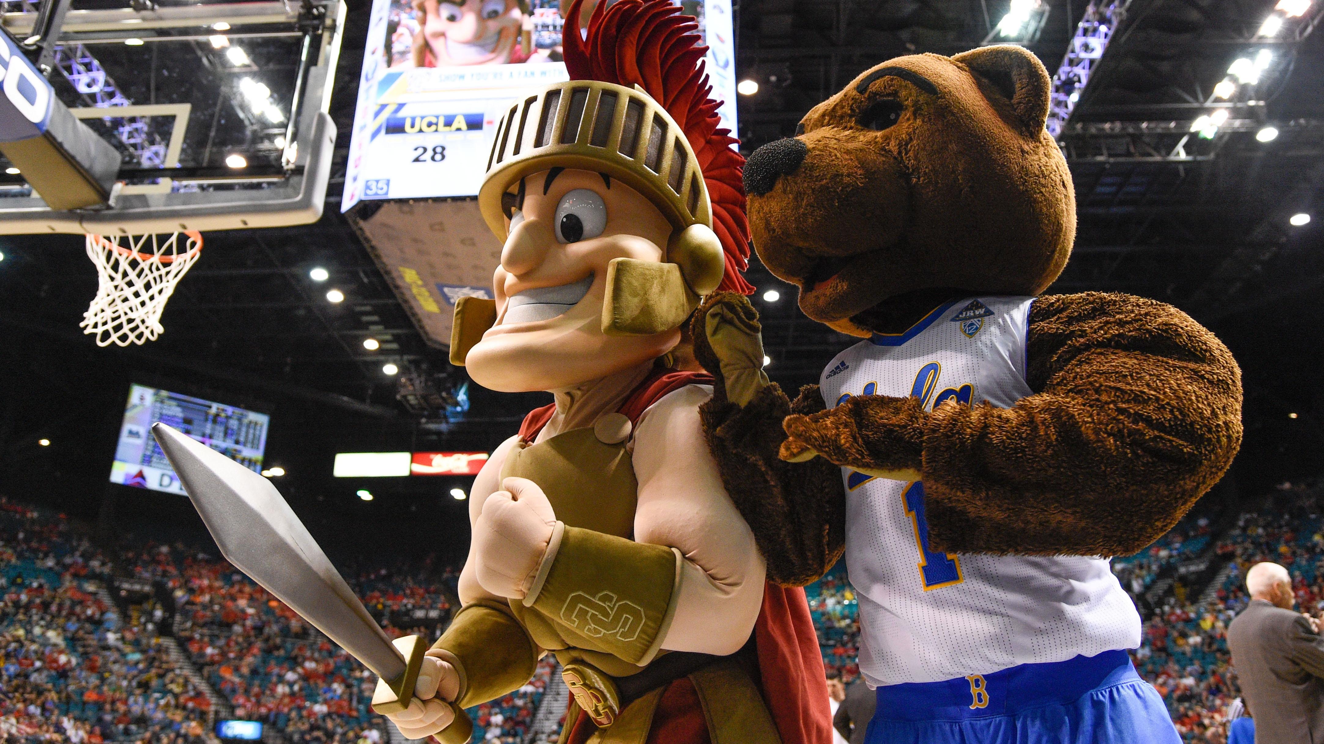 The mascots for USC and UCLA pose at a basketball game.